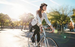 Frau mit Business-Gewand und Tasche auf Fahrrad